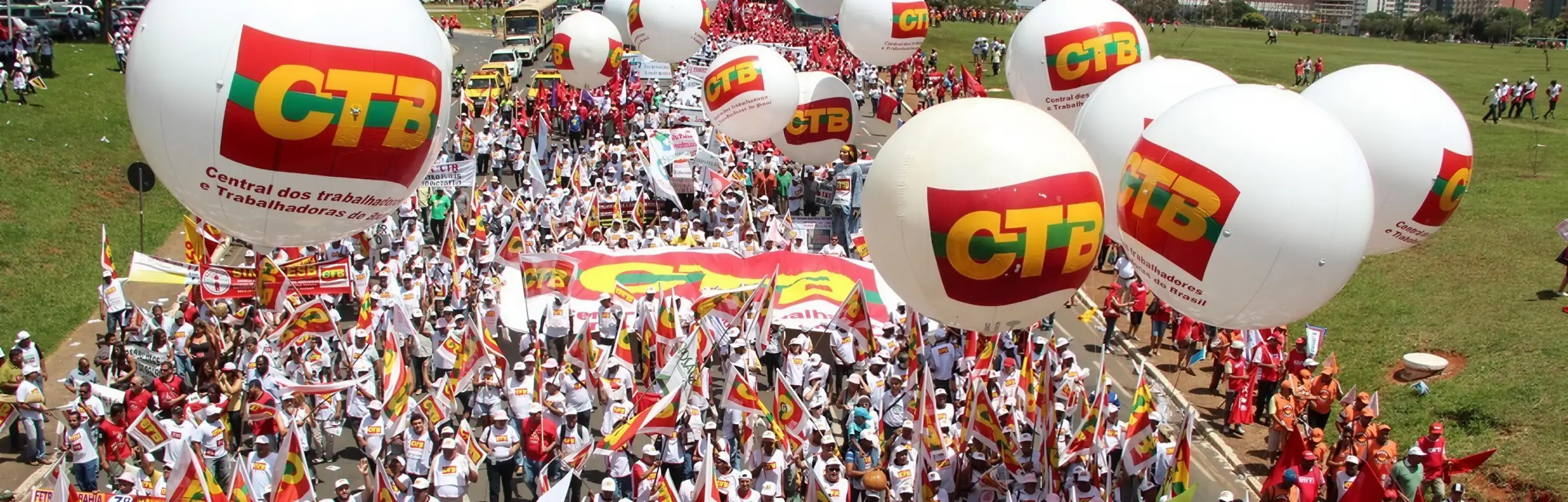 Ato com balões brancos com o logo da CTB sobre uma multidão de trabalhadores com bandeiras
